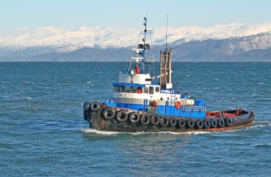 Blue tugboat in the bay clipart