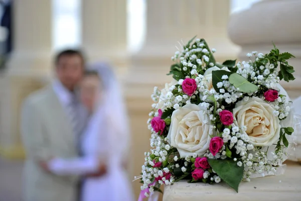 Wedding bouquet against the groom and the bride — Stock Photo, Image