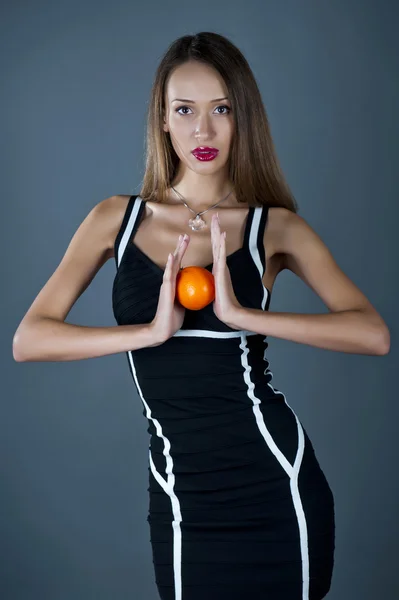 Young model with an orange in hands — Stock Photo, Image