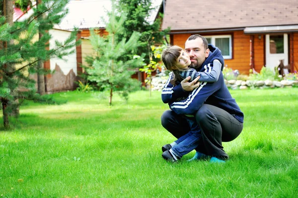 Отец и дочь обнимаются на лужайке — стоковое фото