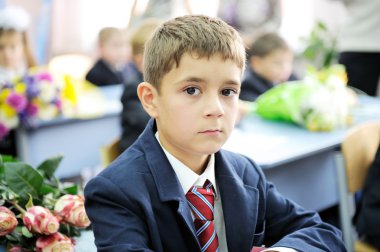 Portrait of first-grader boy sitting at his desk clipart