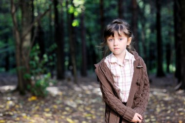 Portrait of adorable child girl in autumn forest clipart