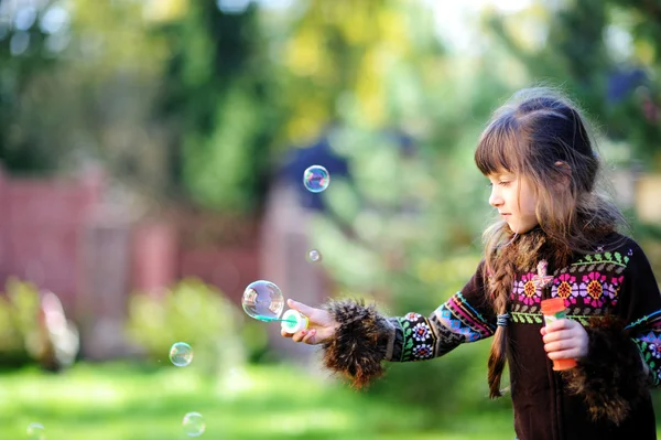 Roztomilá dívka se baví s mýdlové bubliny venku — Stock fotografie