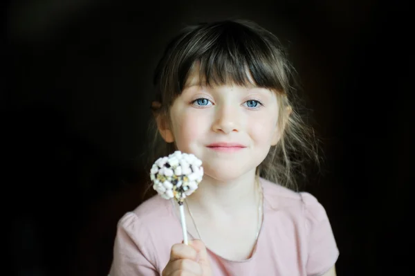 Grappige kind meisje tonen een marshmallow cake — Stockfoto