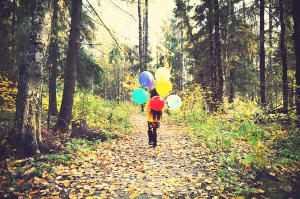 Child girl with balloons in autumn forest — Stock Photo, Image