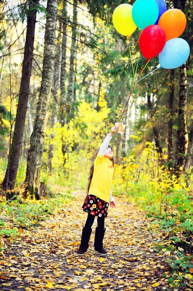 Menina com balões na floresta de outono — Fotografia de Stock
