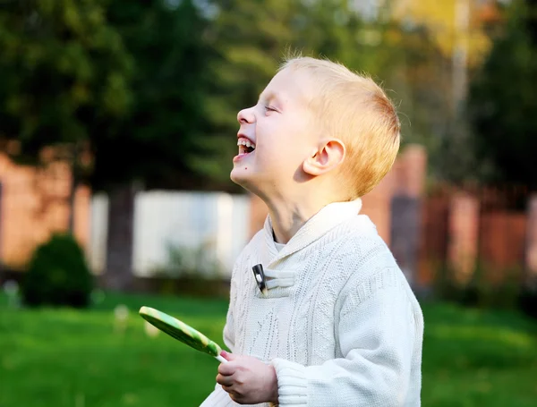 Смішний маленький хлопчик з великим льодяником сміється — стокове фото