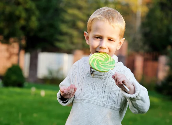 Liten pojke med stora lollipop på en pinne — Stockfoto