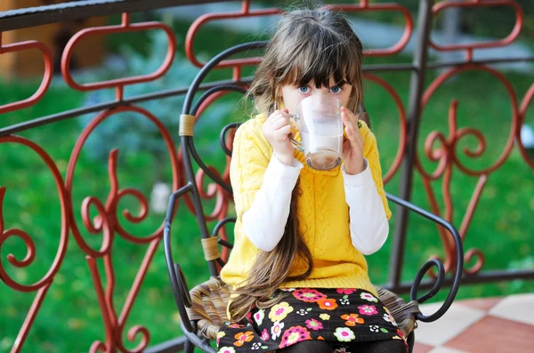 Słodkie dziecko dziewczynka siedzi przy filiżance herbaty na zewnątrz — Zdjęcie stockowe