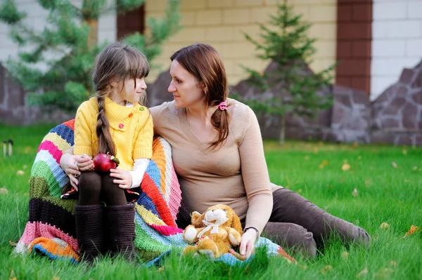 Junge Mutter sitzt mit Tochter auf dem Rasen — Stockfoto