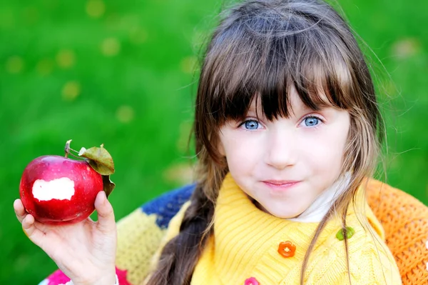 Смішна дівчинка їсть яблуко на відкритому повітрі — стокове фото