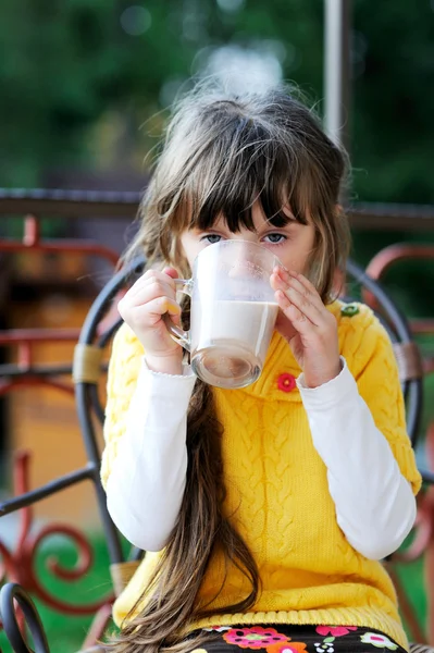 Schattig kind meisje zit met een kopje thee buitenshuis — Stockfoto