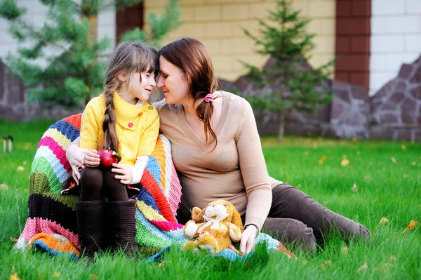 Jeune mère assise avec sa fille sur une pelouse — Photo
