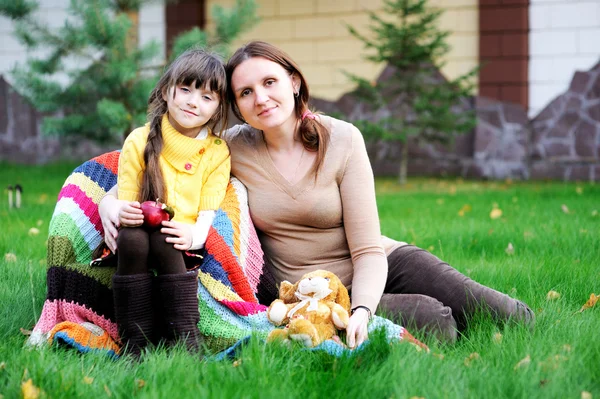 Mladá matka sedí s dcerou na trávníku — Stock fotografie