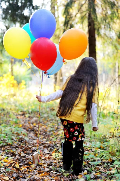 Barn flicka med ballonger i höst skog — Stockfoto
