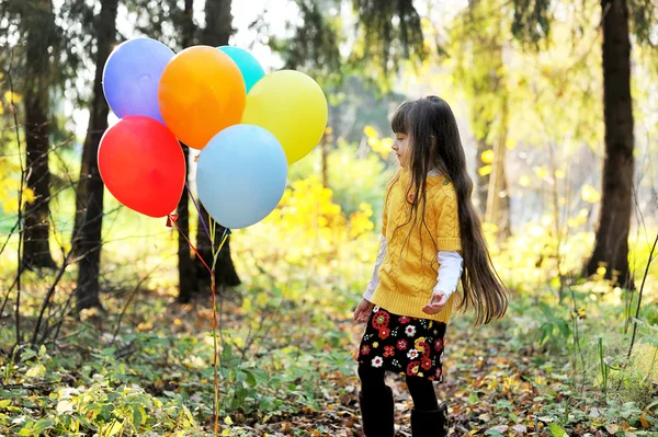 Παιδί κορίτσι με μπαλόνια στο φθινόπωρο δάσος — Φωτογραφία Αρχείου