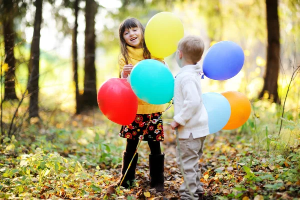 Mały chłopiec i dziewczynka z balonami w lesie — Zdjęcie stockowe