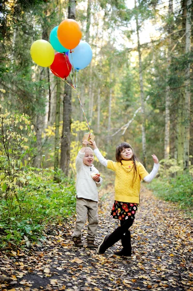 Mały chłopiec i dziewczynka z balonami w lesie — Zdjęcie stockowe