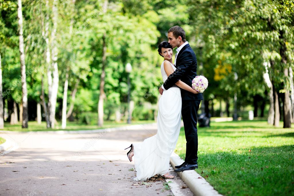 Bride and groom walking in a summer park