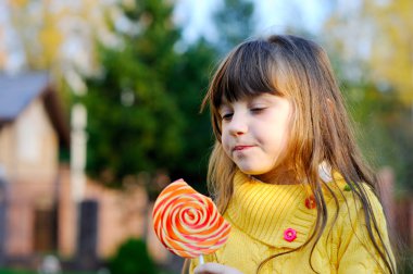 büyük lolipop yiyen sevimli küçük kız portresi