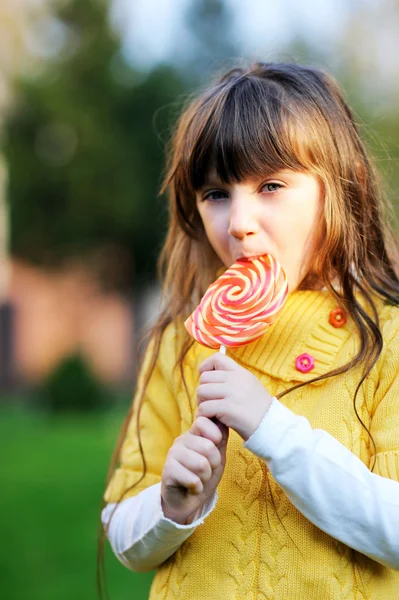 Портрет милої маленької дівчинки, що їсть великий льодяник — стокове фото