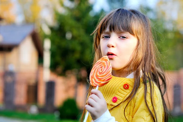 大きなロリポップを食べるかわいい女の子の肖像画 — ストック写真