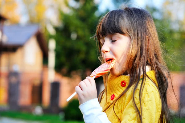 Büyük lolipop yiyen sevimli küçük kız portresi — Stok fotoğraf