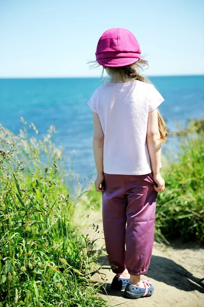Menina em chapéu de sol rosa olhando para o oceano — Fotografia de Stock
