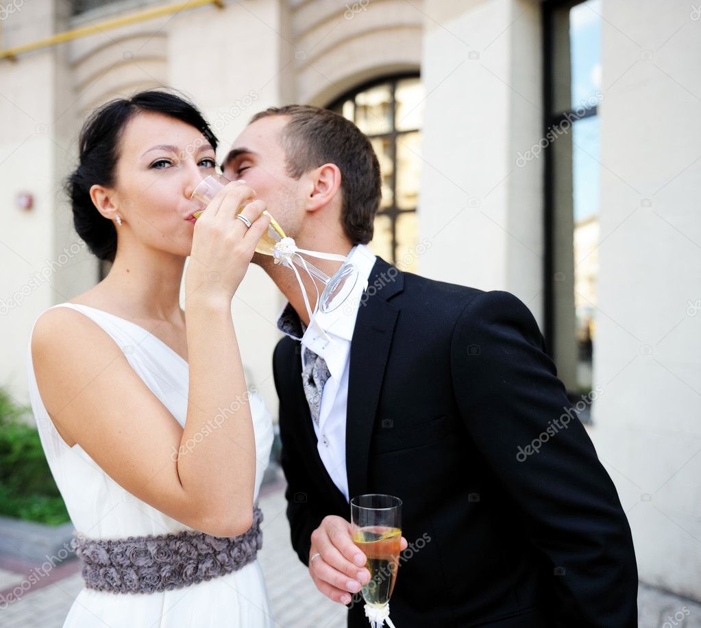 Bride and groom drinking champagne outdoors
