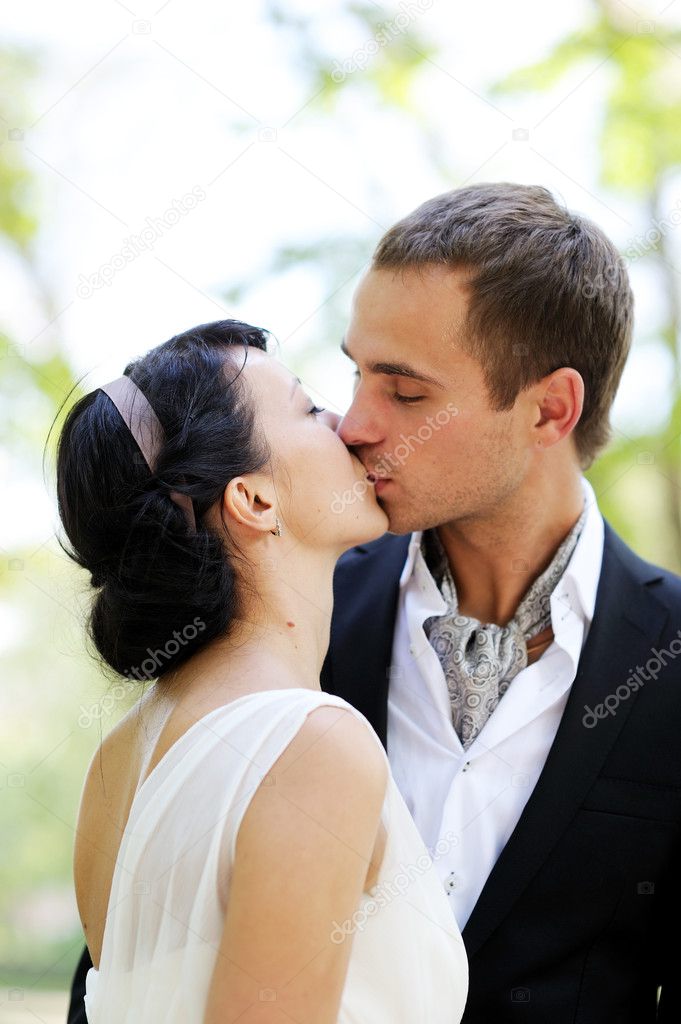 Bride and groom kissing each other outdoors