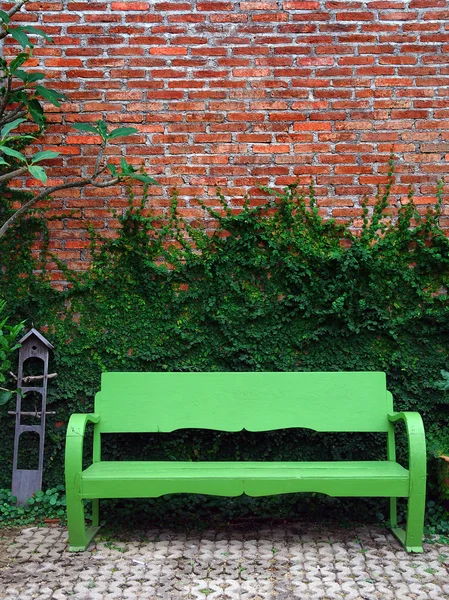 El banco verde y la planta de enredadera en la pared roja — Foto de Stock