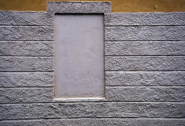A yellow wall and a grey square on a building in a urban scene