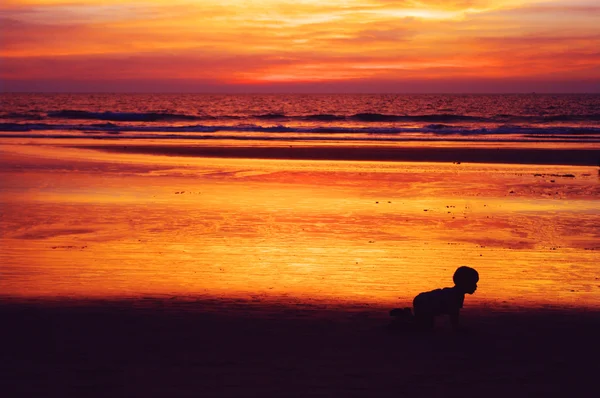 Ребенок ползает по пляжу против упадка — стоковое фото