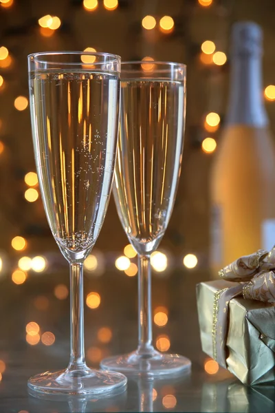 Champagne in glasses and gift on gold background — Stock Photo, Image