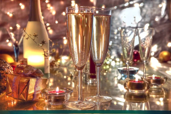 Champagner in Gläsern, Kerzenlicht und Geschenken. — Stockfoto