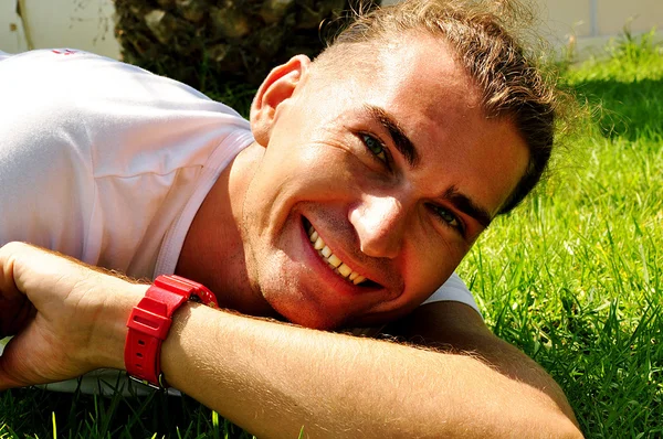 Улыбающийся молодой человек на траве — стоковое фото