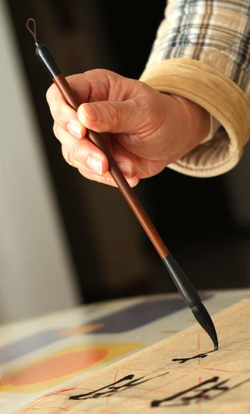 An old man practising calligraphy using a brush pen — Stock Photo, Image