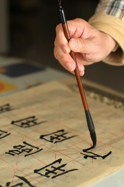 stock image An old man practising calligraphy using a brush pen
