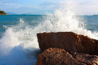 The waves breaking on a stony beach, forming a big spray clipart