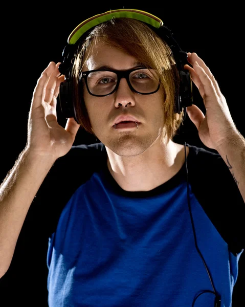 Young man listening to headphones. Studio shot over black. — Stock Photo, Image