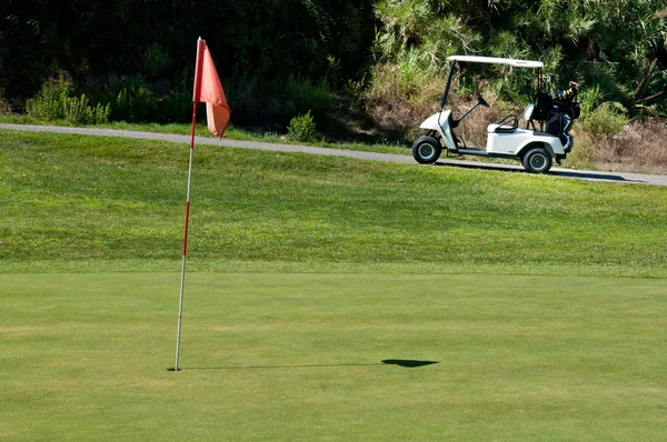 Carrinho de golfe ao lado de um buraco — Fotografia de Stock