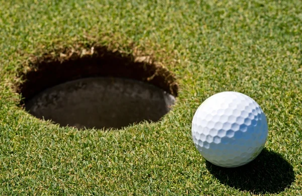 Мяч для гольфа рядом с лункой — стоковое фото