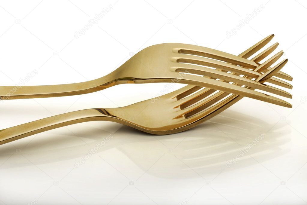 Two gold forks isolated over white background.