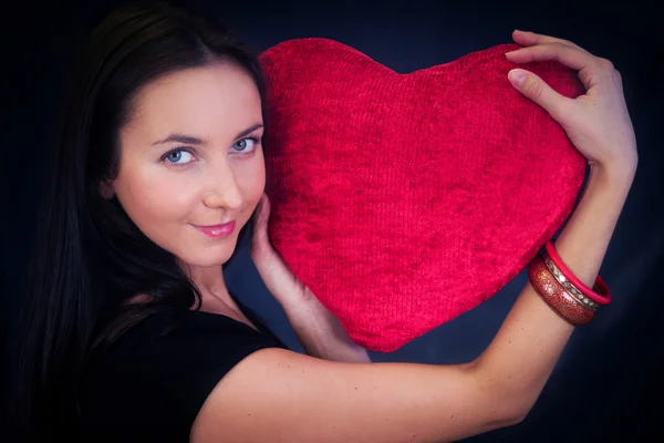 Vrouw met hartvormige kussen — Stockfoto