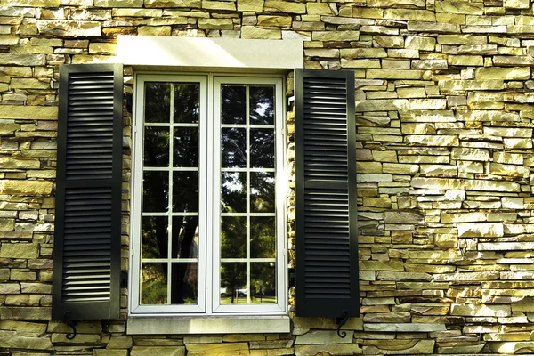 Fönster i en stenmur med fönsterluckor — Stockfoto