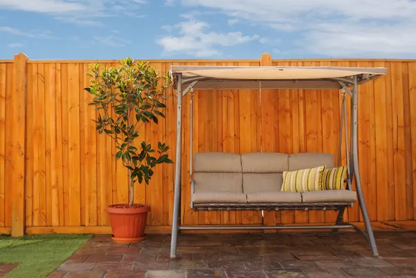 Відкритий гойдалки диван перед дерев'яні кедр паркан — стокове фото
