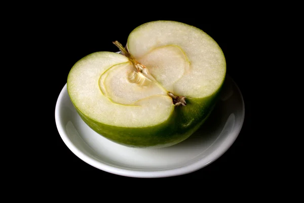 Hälften av ett grönt äpple på en tallrik — Stockfoto