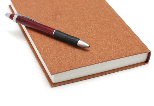 Коричневый дневник лежит на белой поверхности ручкой — стоковое фото