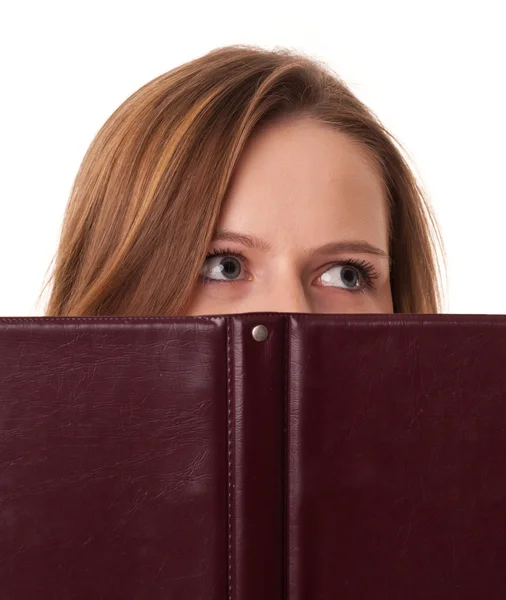 Νεαρή γυναίκα κρύβει το στόμα της πίσω από το βιβλίο — Φωτογραφία Αρχείου