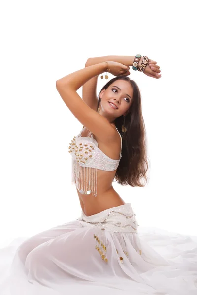 Jonge vrouw buikdanseres in wit kostuum zittend op de vloer — Stockfoto